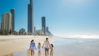 A family walking along the sandy beach in Surfers Paradise with city skyscrapers